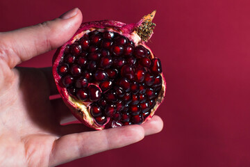 hand holding pomegranate on red background