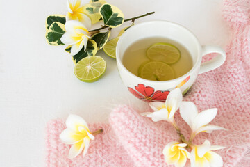 herbal honey lemon healthy drinks health care for sore throat with pink  knitting wool scarf of lifestyle woman relax in winter season and flowers frangipani decorate on background white wooden