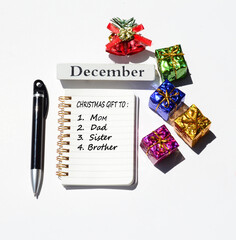 Christmas gift to mum dad sister brother written on notepad with christmas decorations background