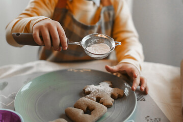 Preparing Gingerbread Cookies in Kitchen for December Holidays sprinkle with powdered sugar