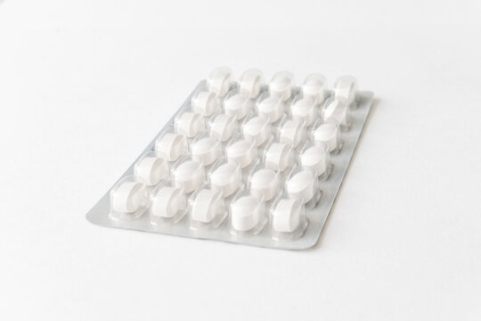 White pills tablets in package on a white background. Capsule pills in plastic pack for pharmacy and medicine.
