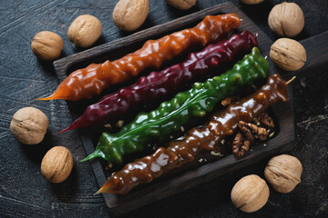 Wooden serving tray with georgian traditional candies churchkhelas, horizontal shot on a dark brown...