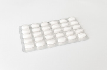 White pills tablets in package on a white background. Capsule pills in plastic pack for pharmacy and medicine.