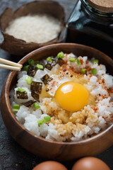 Close-up of tamago kake gohan or japanese warm rice with raw egg and seasonings in a wooden bowl, vertical shot