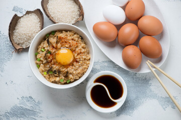 Japanese-style rice and chicken egg bowl or tamago kake gohan, horizontal shot on a white concrete background, above view