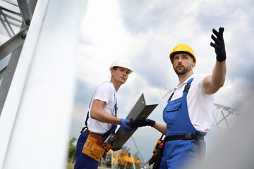 Workers building high voltage tower construction outdoors. Installation of electrical substation