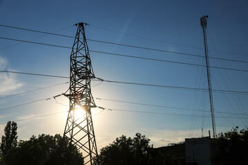 Silhouettes of high voltage tower and trees in evening