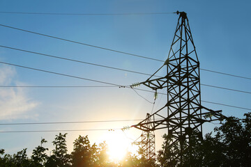 Silhouettes of high voltage tower and trees in evening