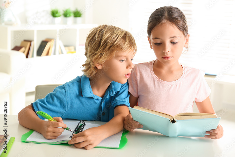 Canvas Prints Little boy and girl doing homework at table indoors