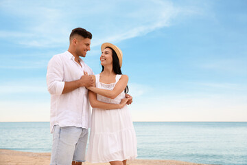 Lovely couple dancing on beach near sea. Space for text