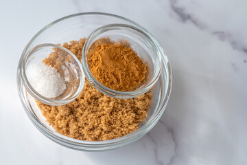Brown sugar, salt and cinnamon close up in a bowl on marble background, copy space