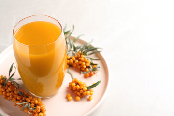 Delicious sea buckthorn juice and fresh berries on light grey marble table, closeup. Space for text