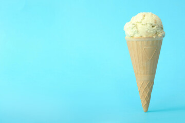 Delicious ice cream in waffle cone on light blue background. Space for text