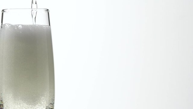 Jet Of Champagne Of Carbonated Drink Or An Alcoholic Cocktail Is Poured Into Glass On A White Background.