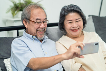 Fototapeta premium Asian senior couple making video call via smartphone with their child.