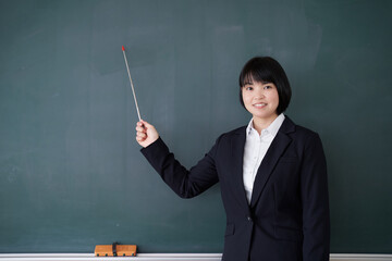 教室で黒板を指す日本人女性教師