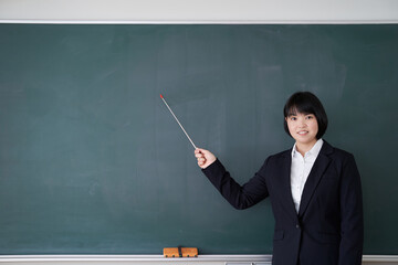 教室で黒板を指す日本人女性教師