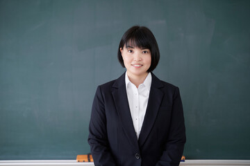 教室で黒板の前で立つ日本人女性教師