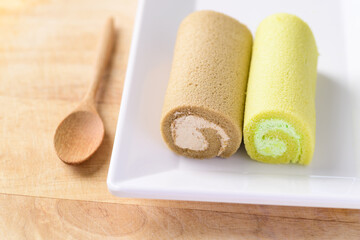 Coffee roll cake and Pandan roll cake on white dish with spoon ready to eating