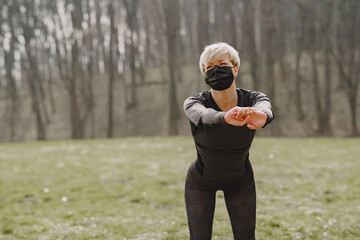 Woman in mask. Girl in a park. Coronavirus theme. Woman training.