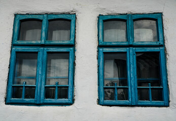Fototapeta na wymiar old blue windows to a house painted white