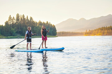 Fototapeta na wymiar Family Paddle boarding together on a Beautiful Mountain Lake