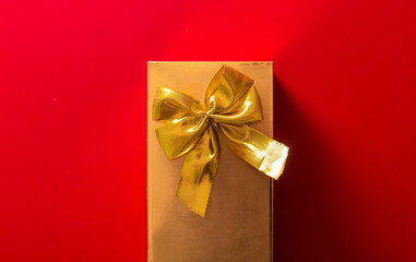 Gift in a golden package with a bow on a red background