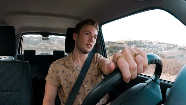 A caucasian man driving a car on a bumpy road. Car interior point of view