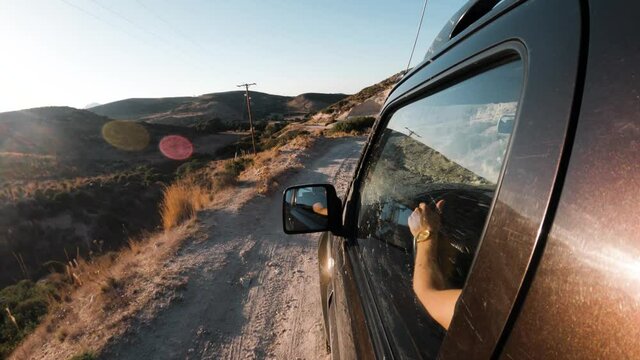 A 4wd car driving on a bumpy dirt road at golden hour. Left door pov
