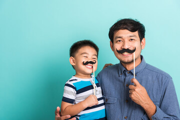 Family funny happy hipster father and his son kid holding black mustache props for the photo booth...