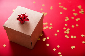 Gift wrapped on a red background and golden confetti
