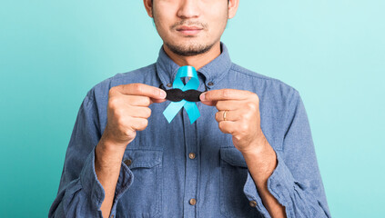 Asian portrait happy handsome man posing he holding a light blue ribbon and mustache, studio shot...