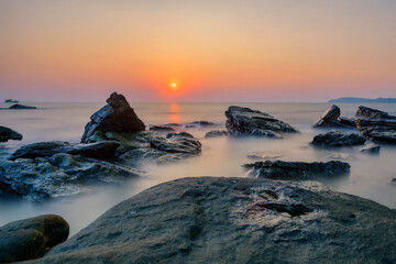 Sunrise over the sea, close-up of rocks on the coast