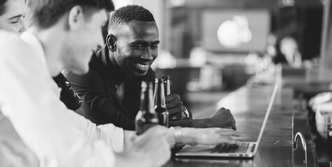 handsome young African American man looking at laptop computer screen. Black businessman and friends video call on laptop computer at the club.