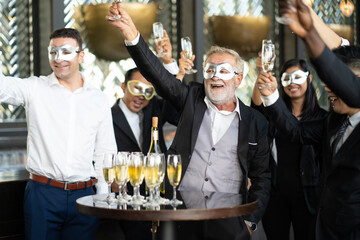 Masquerade party. Beautiful women and men wearing fantasy mask. Company employee enjoy drinking in mask party  together indoors celebration