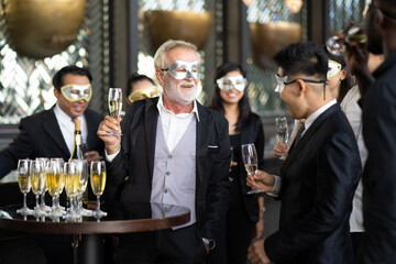 Masquerade party. Beautiful women and men wearing fantasy mask. Company employee enjoy drinking in mask party  together indoors celebration