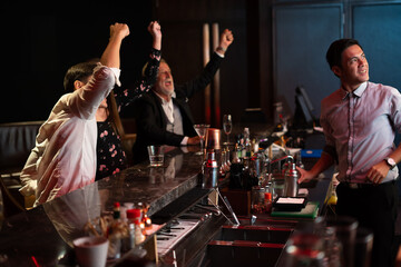 Peoples having fun watching football game on TV and drinking beverages at bar counter in nightclub