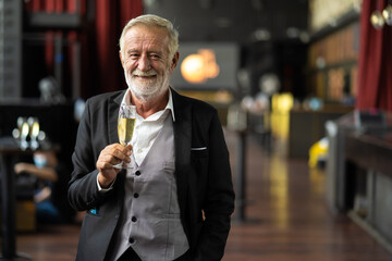 portrait of smiling senior man holding champagne glass at the birthday party.