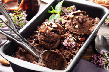 Chocolate icecream in metal tray with mint leaf and almond nuts