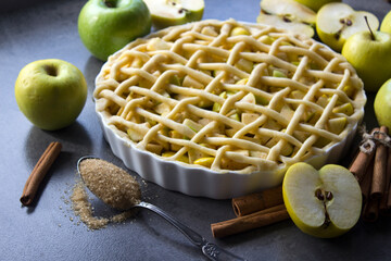 Apple pie preparation. Unbaked apple pie with fresh apples on a table. Grey background. 
