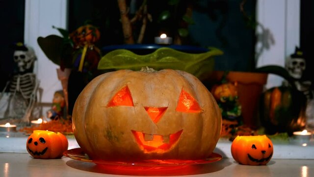 Home decoration with spooky glows halloween pumpkin head Jack Lantern face and burning candle. Carved eyes, mouth. Traditional Halloween symbol. Close-up.