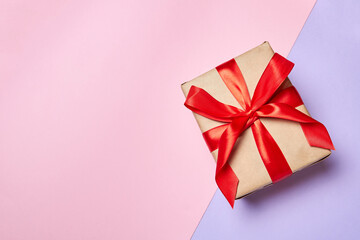 Christmas or New Year gift box with red ribbon on a colorful background