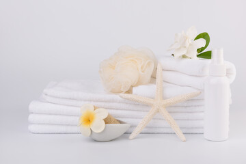 Spa and health care concepts setup with stack of white towels star fish,Gardenia flowers,spray bottle,and loofah scrub on white background