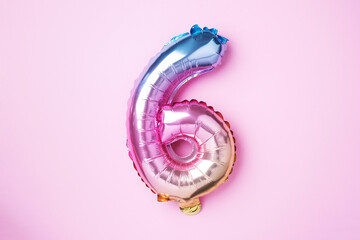 Creative layout. Rainbow foil balloon number and digit six 6. Birthday greeting card. Anniversary concept. Top view. Copy space. Stylish colored numeral over pink background. Numerical digit.