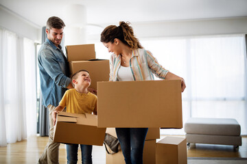 Happy young family unpacking cardboard boxes at new home