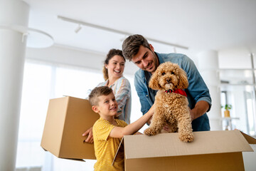 Happy family with children moving with boxes in a new apartment house.