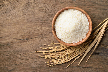 Flat lay (top view) of White jasmine rice with paddy rice ears on wood background.