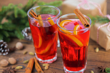 Mulled wine in glass glasses decorated with cinnamon sticks on a wooden table, nearby are green spruce branches, cones. Christmas drink, New Year's punch.