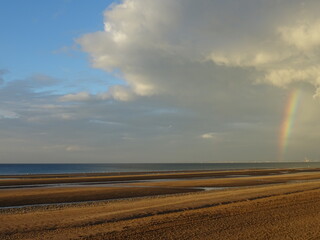 stormy sky and rainbow on the atlantic coast on the sandy beach in France
