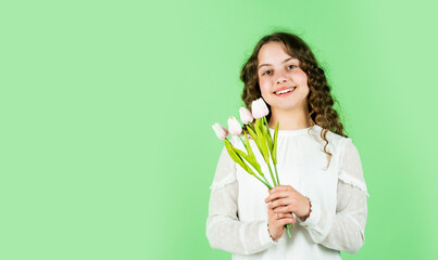 spring flower bouquet. happy womens day. international childrens day. mothers day concept. cheerful little girl with curly hair. tulips flowers for child. happy girl hold tulip flowers. copy space